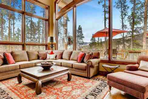Spacious living room with large windows overlooking forest scenery.