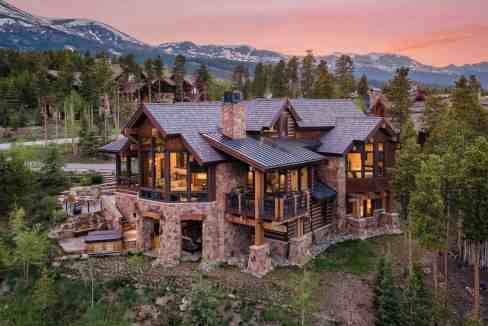Elegant mountain lodge with large windows and scenic views at sunset.