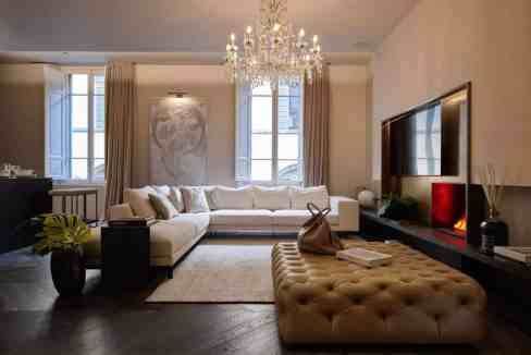 Luxurious living room with chandelier, modern decor, and large windows.