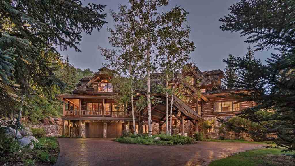 Elegant mountain lodge surrounded by trees and nature at dusk.