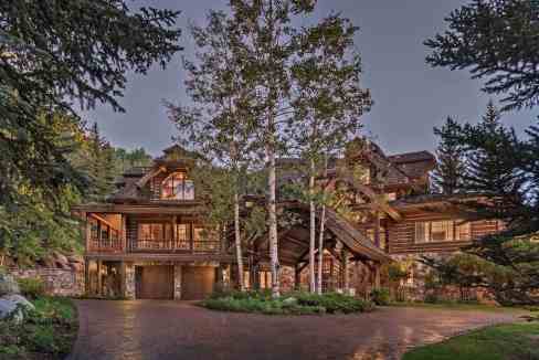 Elegant mountain lodge surrounded by trees and nature at dusk.