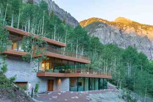 Contemporary mountain villa with large glass windows and expansive decks in a forested setting.