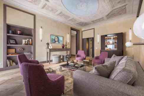 Luxurious living room with purple and gray furniture, ornate ceiling, and modern decor.