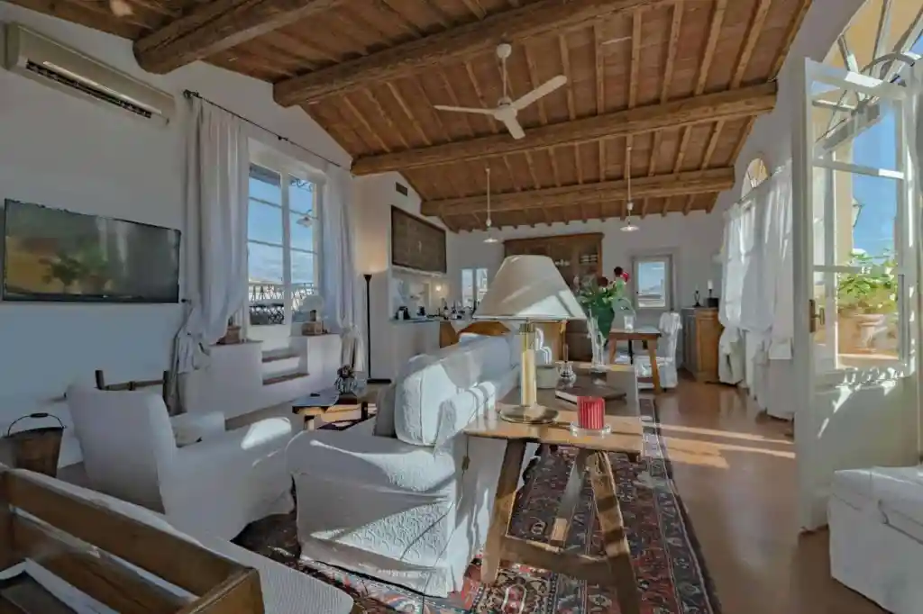 Bright living room with wooden ceiling, white furniture, and large windows in Florence.