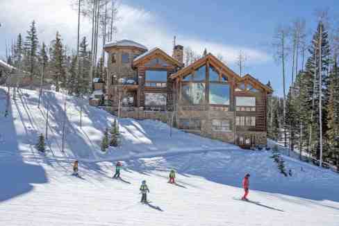 Elegant mountain cabin with large windows in a snowy setting.
