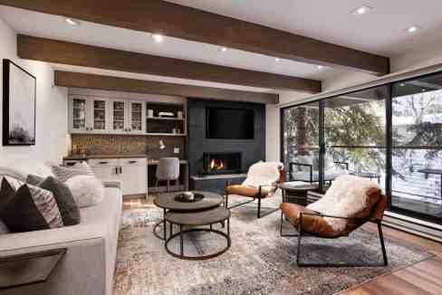 Modern living room with fireplace, large windows, and stylish furniture.