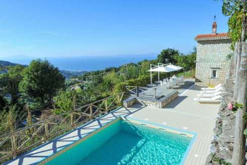 Luxury villa with infinity pool overlooking the sea and lush greenery.