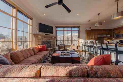 Bright living room with large windows and mountain scenery, modern decor, and cozy seating.