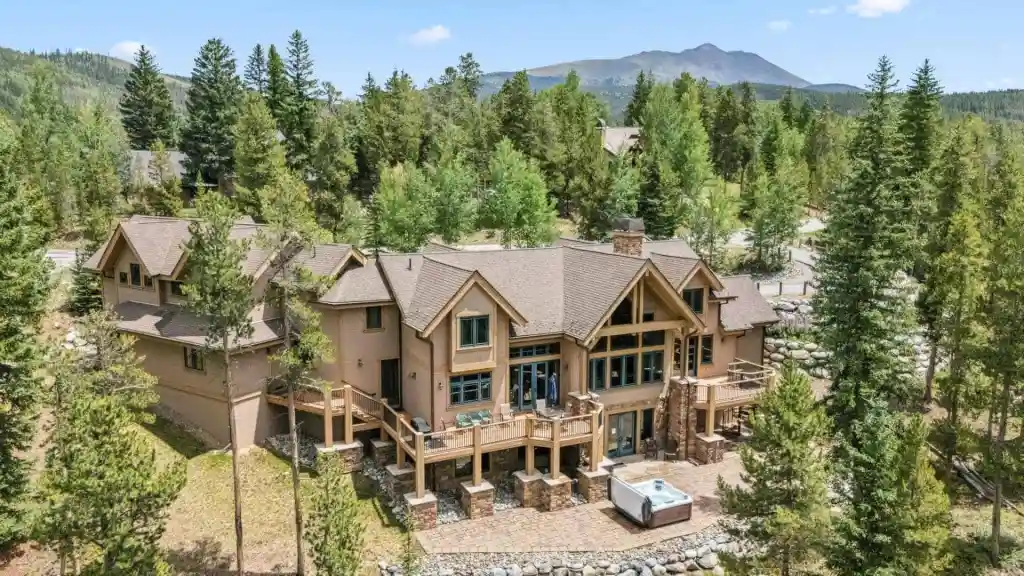 Spacious mountain chalet surrounded by tall pine trees and scenic mountain views.