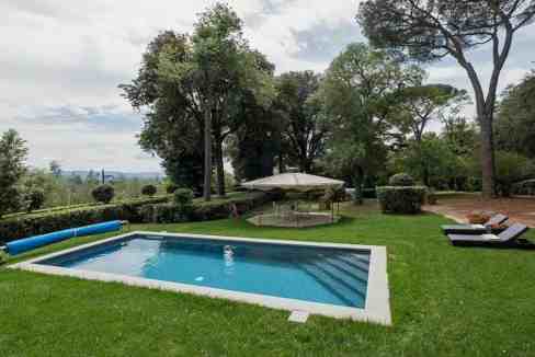 Elegant villa with swimming pool, lush garden, and outdoor lounge area.