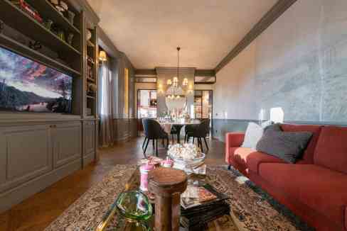 Stylish living room with red sofa, chandelier, and large TV for luxury apartment.