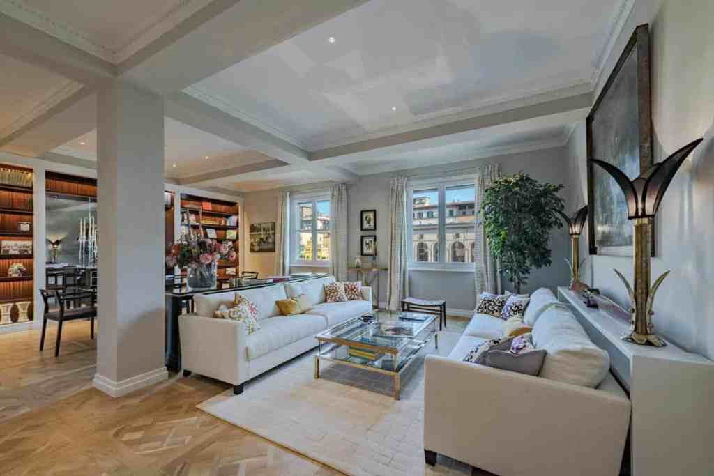 Luxurious living room with white sofas, large windows, and elegant decor.