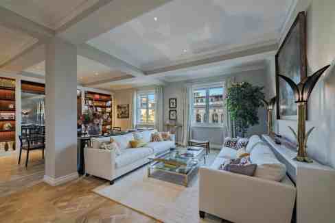 Luxurious living room with white sofas, large windows, and elegant decor.