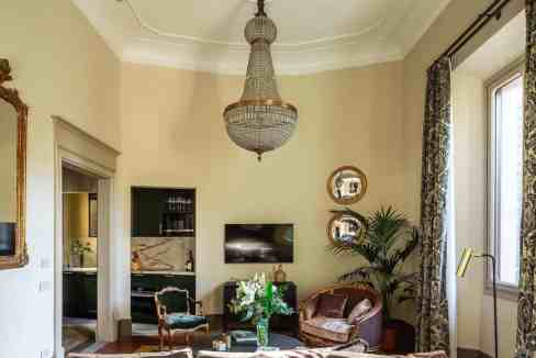 Luxurious living room with chandelier, vintage furniture, and large windows.