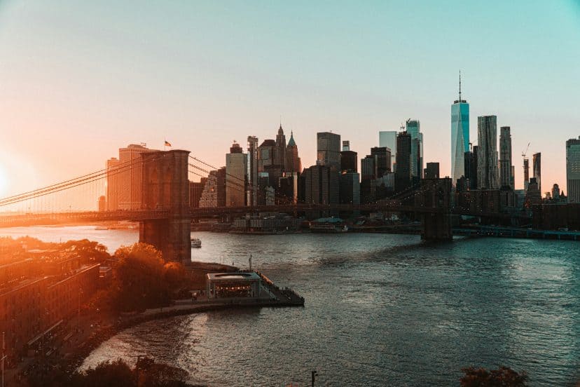 Sunset over Manhattan skyline with Brooklyn Bridge and East River.