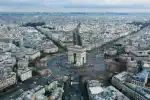 Aerial view of the Arc de Triomphe in Paris with surrounding cityscape.