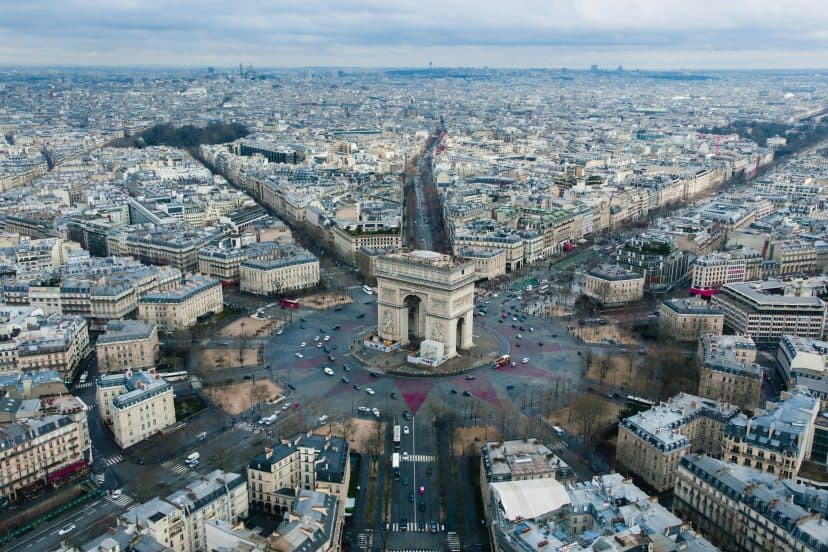 Aerial view of the Arc de Triomphe in Paris with surrounding cityscape.