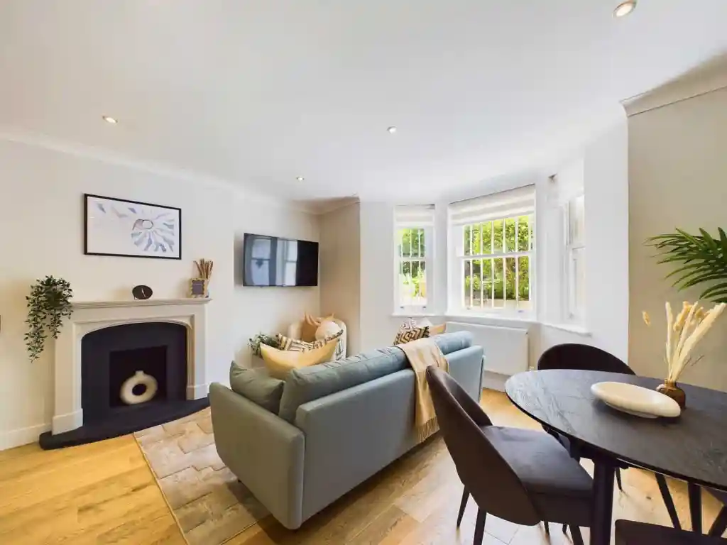 Spacious living room with large windows, modern furniture, and a cozy fireplace.