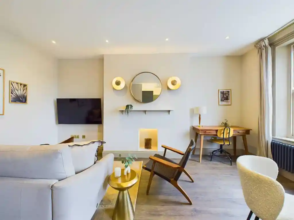 Bright living room with beige sofa, wooden chairs, and large window.
