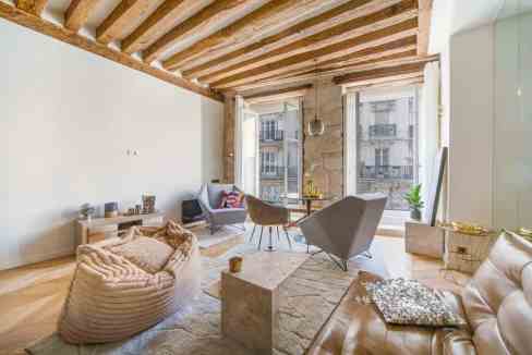 Stylish living room with exposed wooden beams and large windows in Paris.