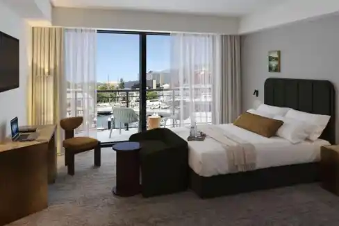 Spacious hotel room with balcony, city view, and contemporary decor.