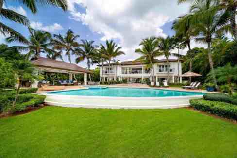 Elegant villa with pool, surrounded by palm trees and lush greenery.