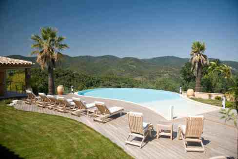 Infinity pool overlooking lush green mountains and clear blue sky.