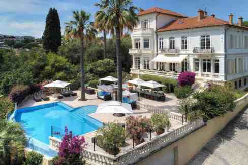 Elegant villa with swimming pool, palm trees, and lush garden in Cannes.
