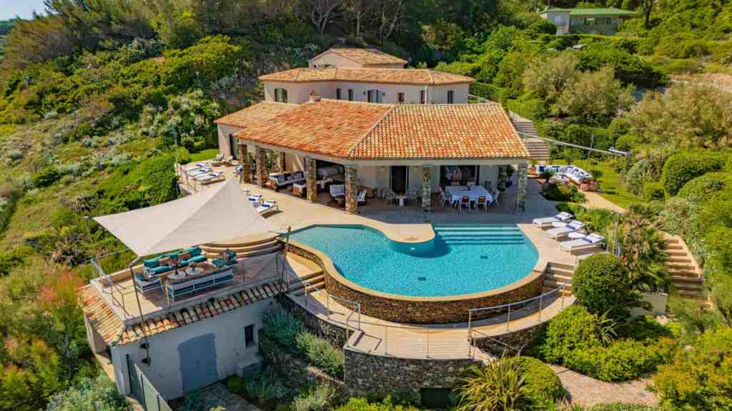 Elegant luxury villa with swimming pool and lush garden in a scenic setting.