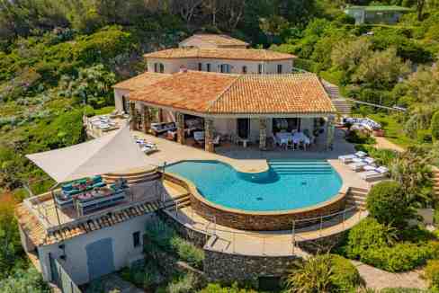 Elegant luxury villa with swimming pool and lush garden in a scenic setting.