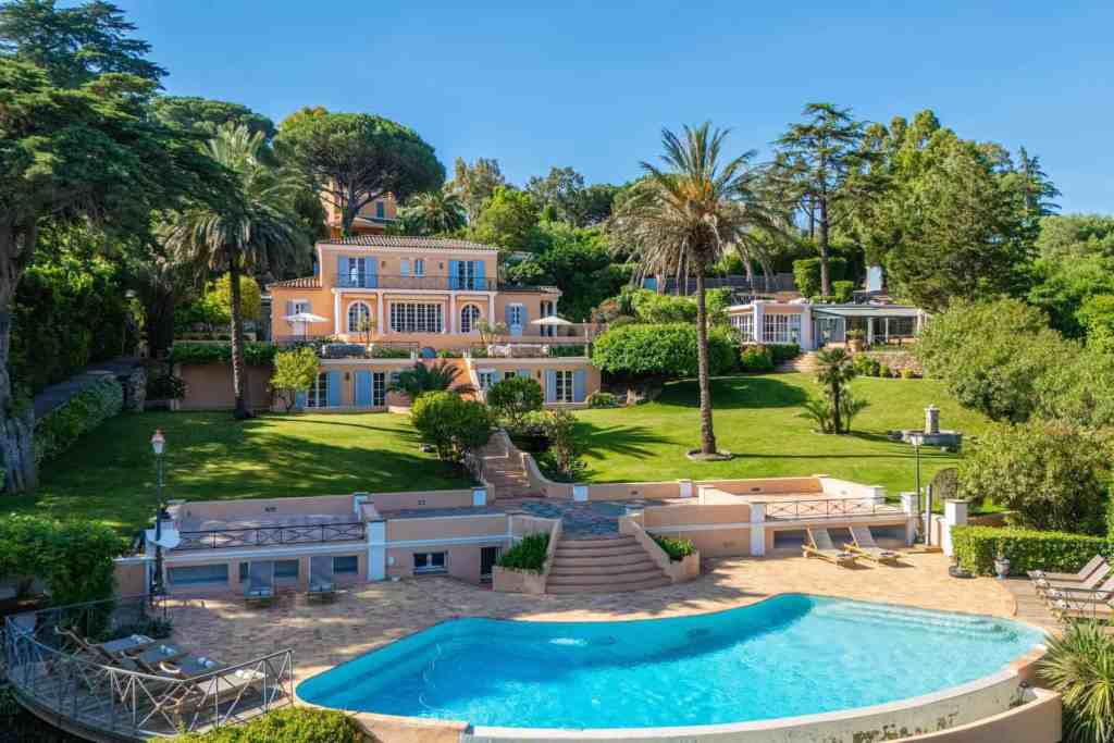 Elegant luxury villa with swimming pool and lush gardens in a scenic setting.