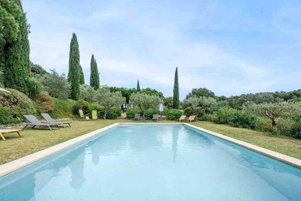 Serene outdoor pool surrounded by lush greenery and tall cypress trees.