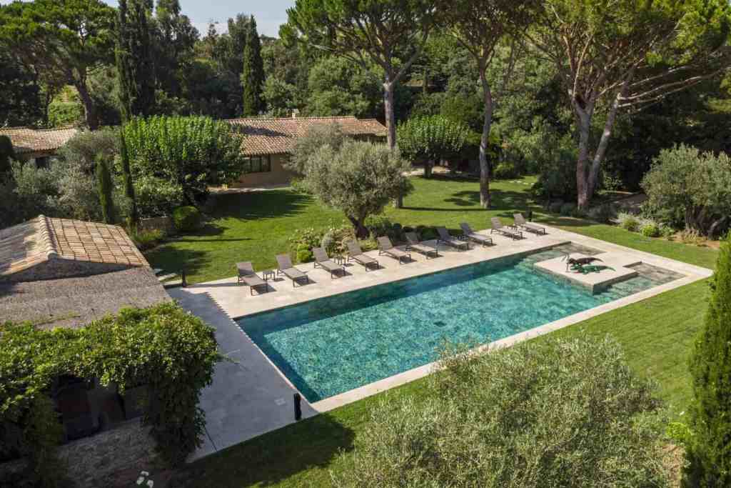 Elegant outdoor pool surrounded by lush greenery and tall trees.