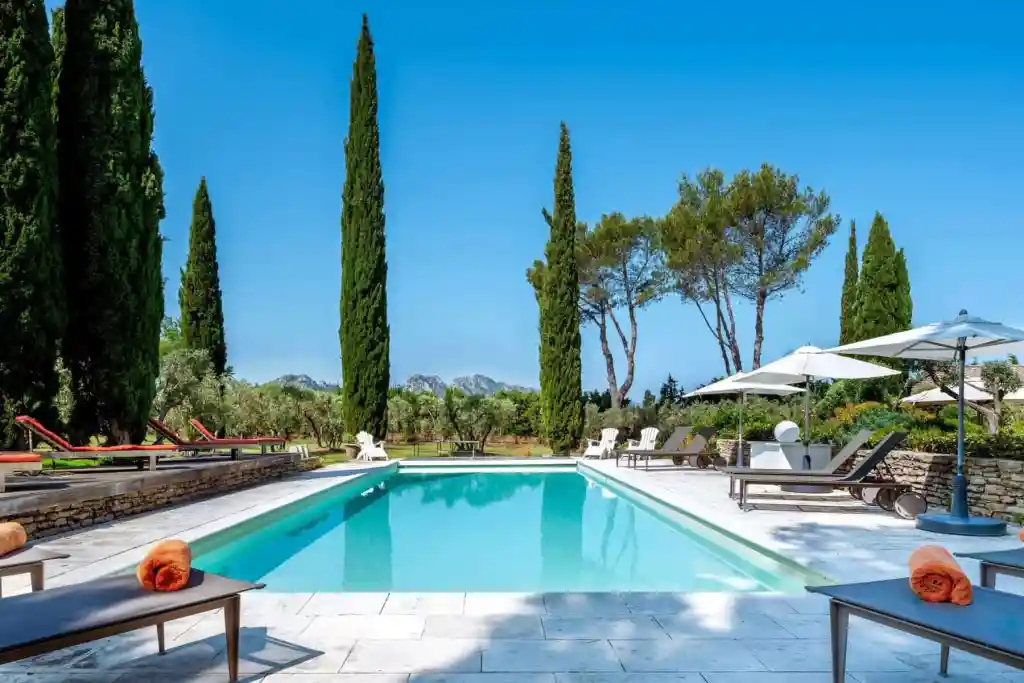 Elegant outdoor pool with sun loungers and cypress trees in Provence.