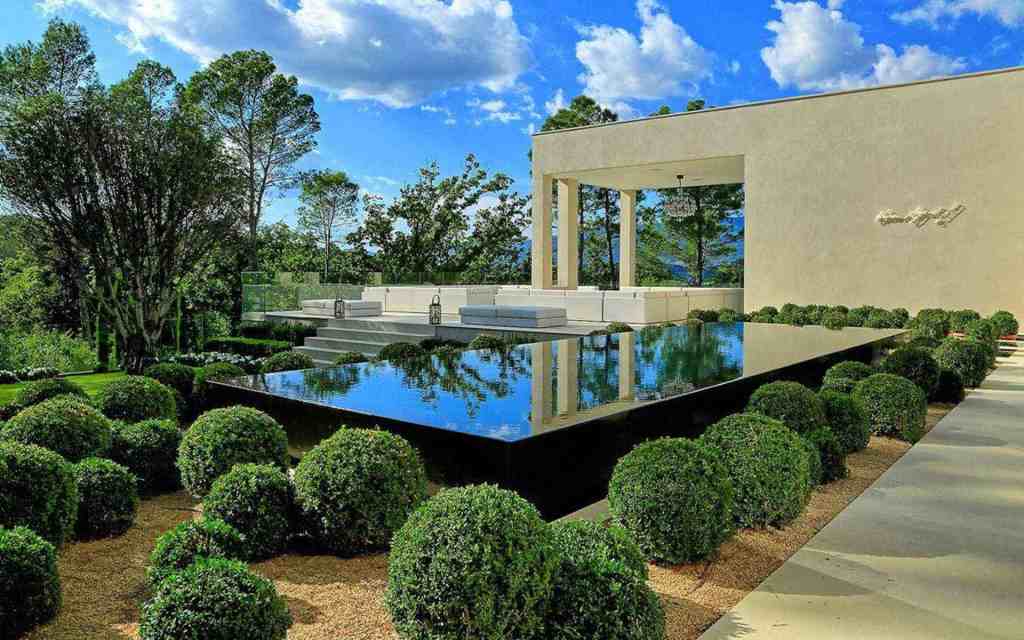 Luxury modern villa with infinity pool and lush garden setting.