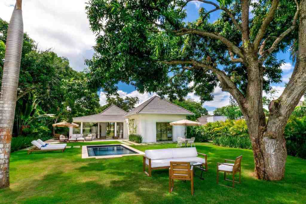Elegant outdoor living space with pool, garden, and shaded seating area.