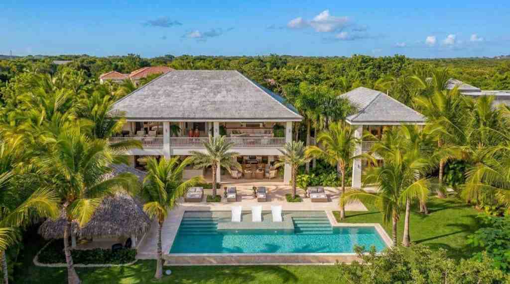 Luxury tropical villa with pool, surrounded by lush greenery and palm trees.
