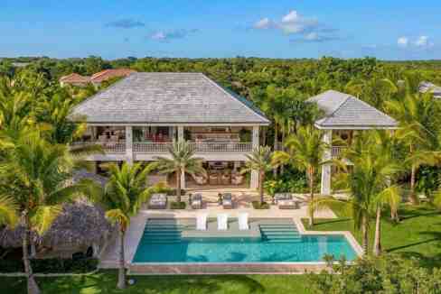 Luxury tropical villa with pool, surrounded by lush greenery and palm trees.