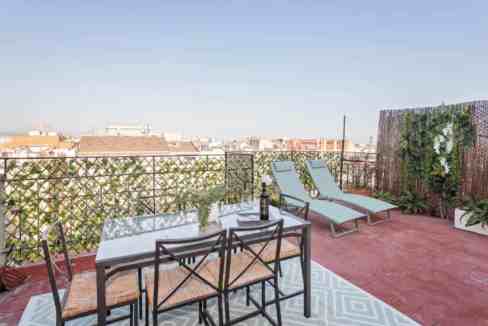 Spacious rooftop terrace with outdoor dining and lounge chairs in Barcelona.