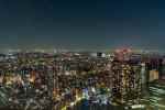 Nighttime cityscape of Tokyo with illuminated skyscrapers and streets.