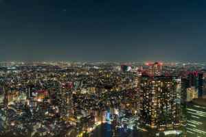Nighttime cityscape of Tokyo with illuminated skyscrapers and streets.