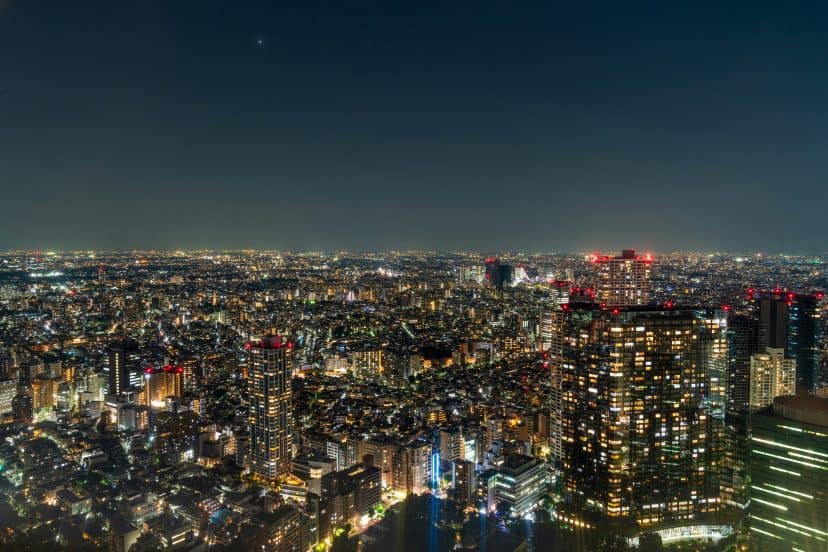 Nighttime cityscape of Tokyo with illuminated skyscrapers and streets.